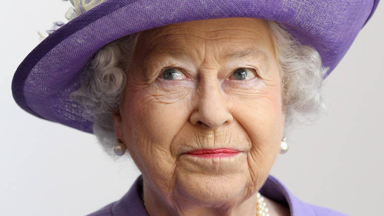La reine Elizabeth sourit légèrement dans sa tenue et son chapeau lavande