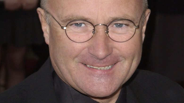 Phil Collins pose avec des lunettes rondes