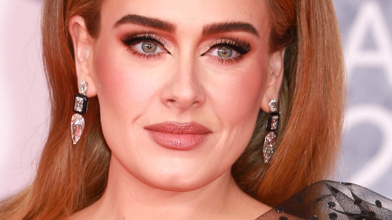 Adele souriante et portant des boucles d'oreilles en diamant