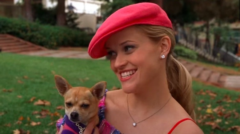 Reese Witherspoon tient un chien en souriant