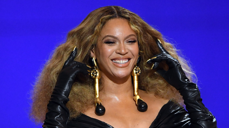 Beyoncé tenant ses cheveux en arrière et souriant