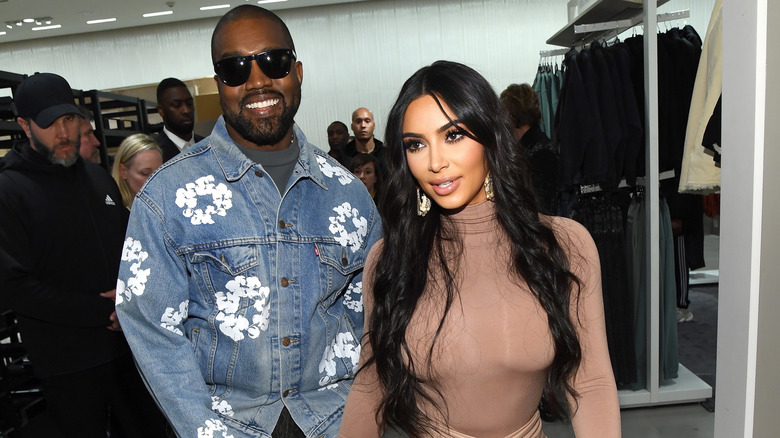 Kanye West souriant derrière Kim Kardashian