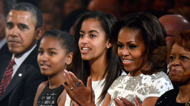 Malia et Sasha applaudissent avec Michelle Obama