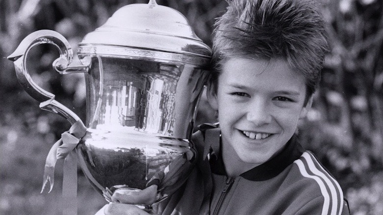 Le jeune David Beckham souriant avec un trophée